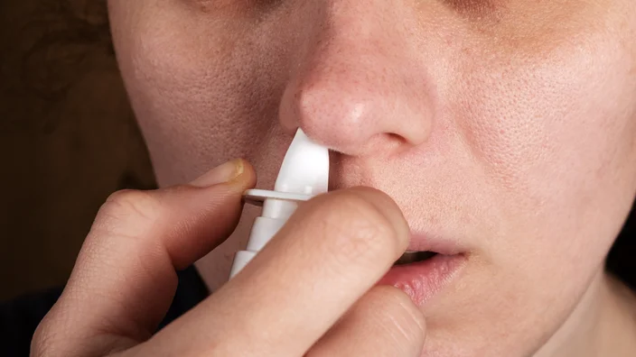 closeup person using nasal spray