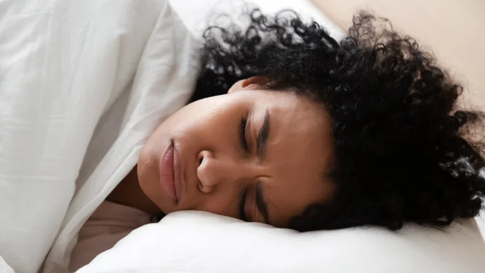 woman with headache laying in bed